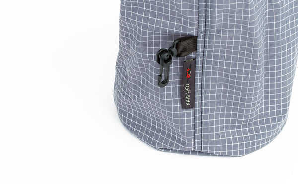 The exterior attachment clip sewn into the exterior side seam of a Northwest Sky (light grey with white grid) 200 Halcyon Yarn Stuff Sack.
